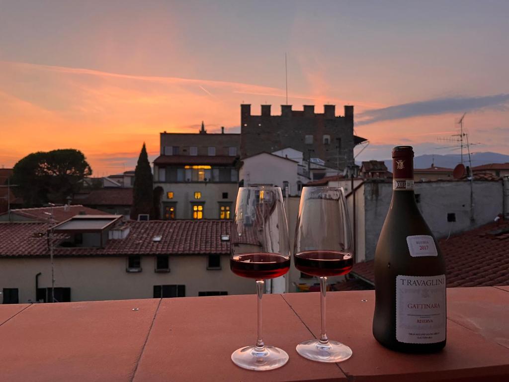 two glasses of wine sitting on a table with a bottle of wine at CasaMancio, loft in heart of medieval Tuscan city in Pistoia