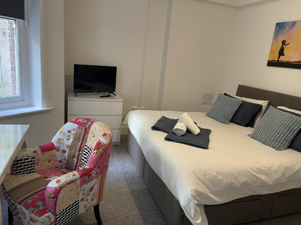 a bedroom with two beds and a chair and a television at The Sand Bank - Flat 1 Abchurch Chambers BH1 in Bournemouth