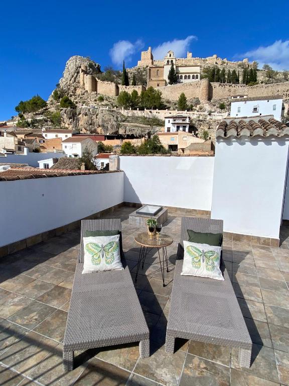 a patio with two chairs and a table with a castle in the background at Balcón de la Plaza in Moclín