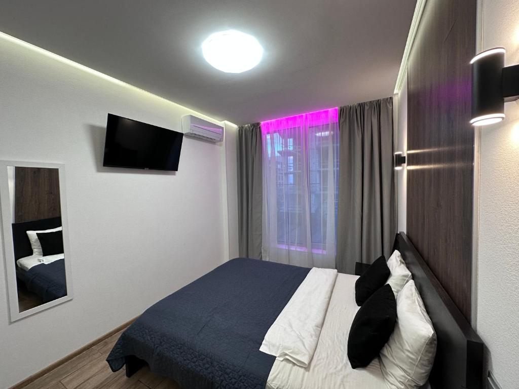 een slaapkamer met een bed en een raam met roze verlichting bij Rybalsky Studio apartment Dnipro view in Kiev