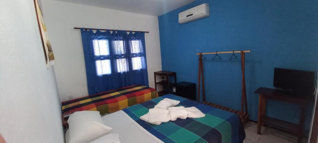 1 dormitorio con 1 cama de arco iris y toallas en EDEN Pousada en Lagoinha