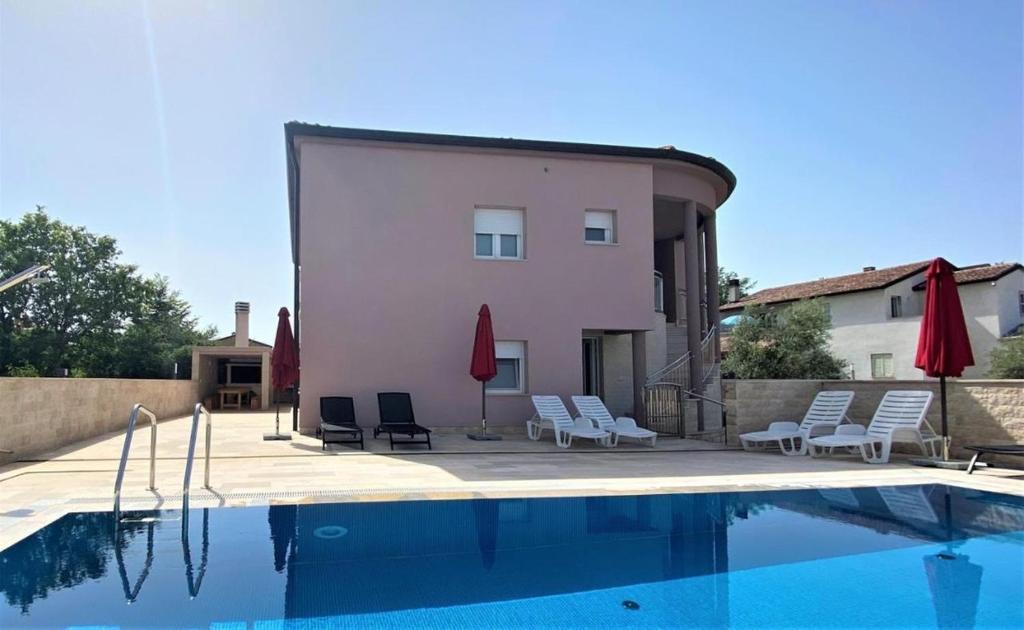a villa with a swimming pool with chairs and umbrellas at Villa Maduna 1 in Kaštel
