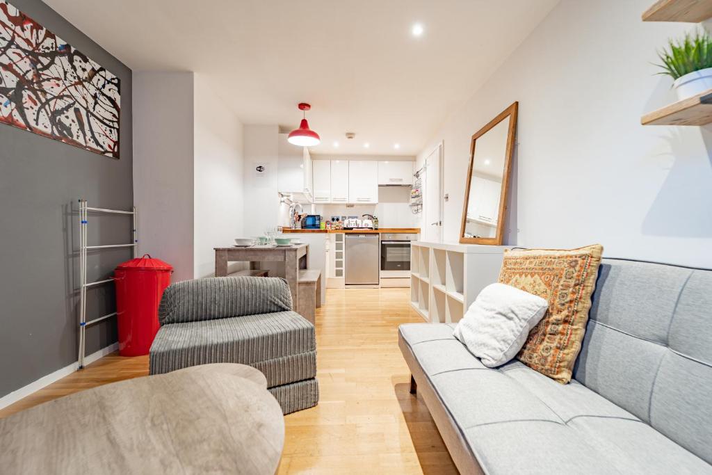 a living room with a couch and a kitchen at Modern flat in PRIME LOCATION near Shoreditch & Brick lane in London