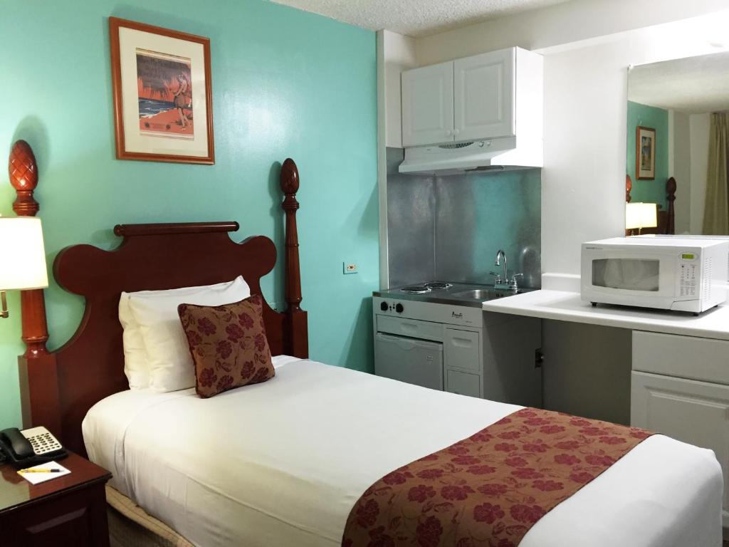 a room with a bed and a kitchen with a microwave at Pagoda Hotel in Honolulu