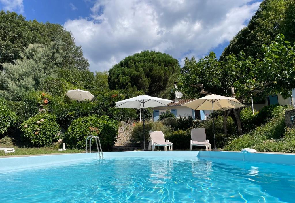 a swimming pool with two chairs and umbrellas at Le Pre du Moulin in Courniou