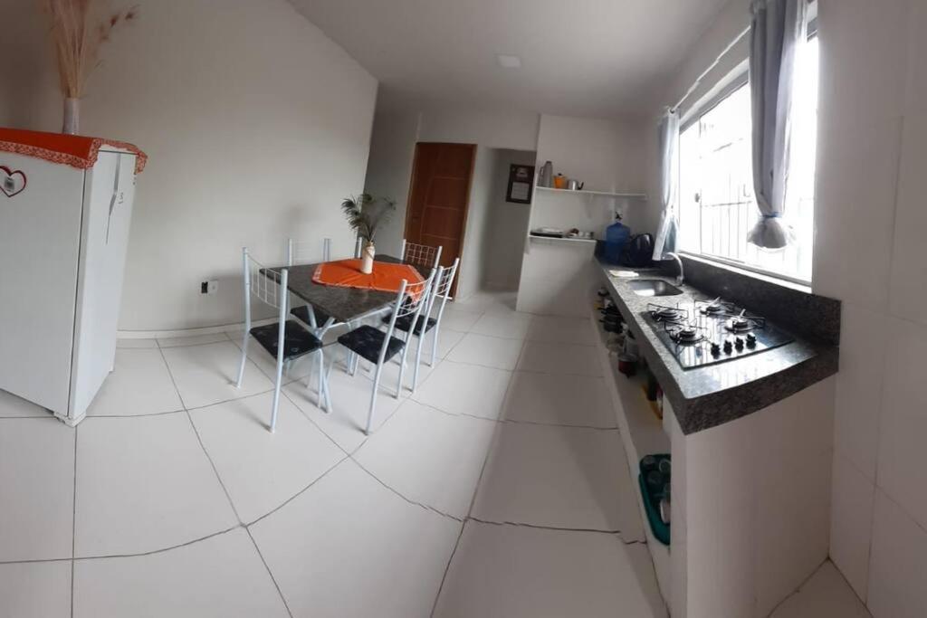a white kitchen with a stove and a table at Residencial Casa Grande- Apto 01 in Santa Cruz Cabrália