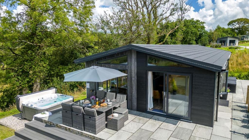 a black shed with a pool and an umbrella at Maple Lodge, 20 Roadford Lake Lodges in Lifton