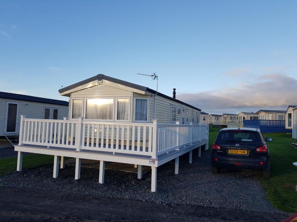 una casa móvil con un coche aparcado delante en 8 berth caravan Turnberry Holiday Park, en Turnberry