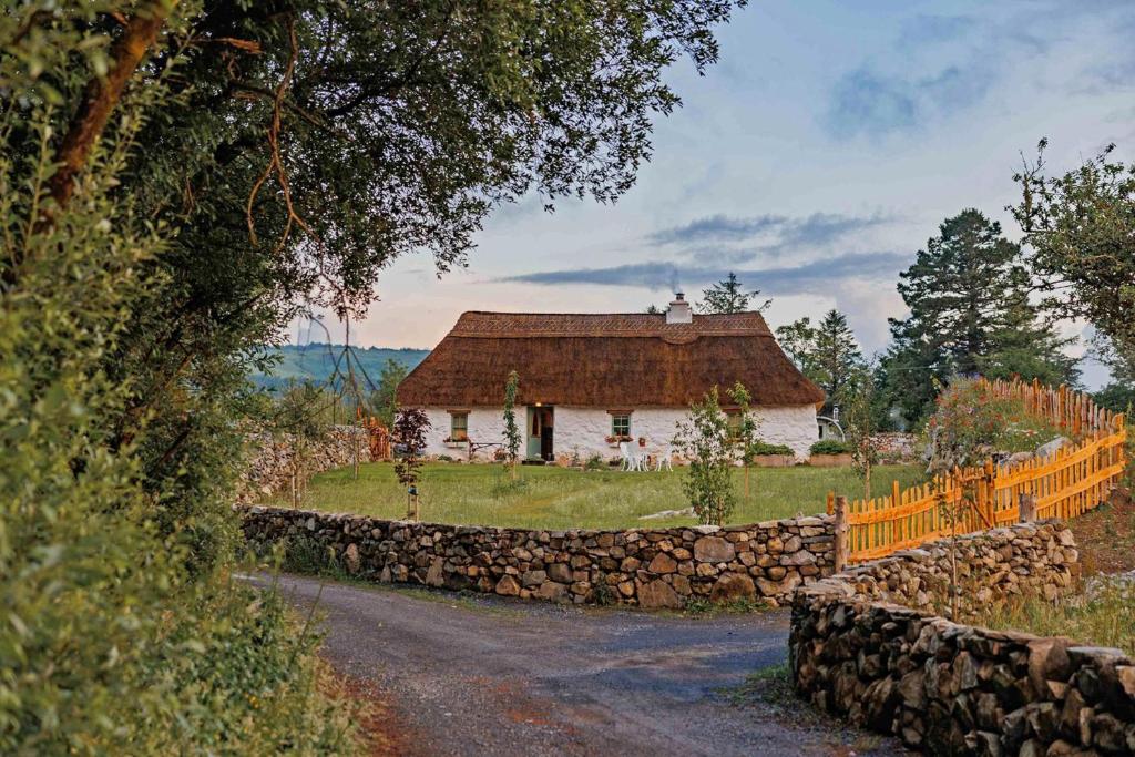 an old house with a stone fence and a road at Patsys Cottage 415 in Rusheeny