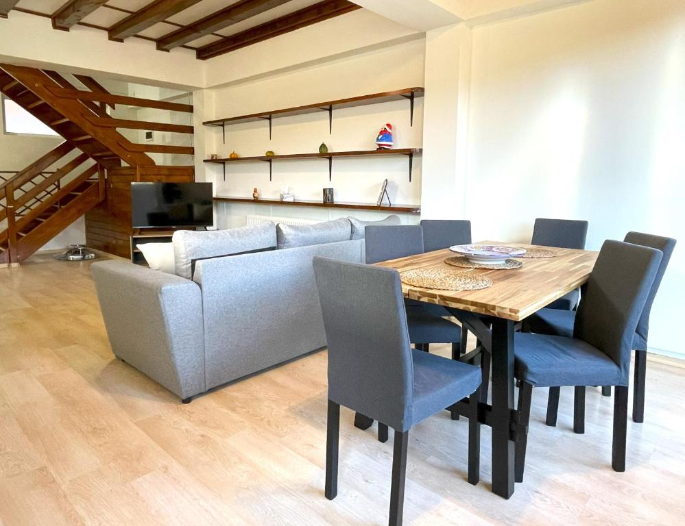 a dining room with a table and a couch at Mountain Escape Loft in Buşteni