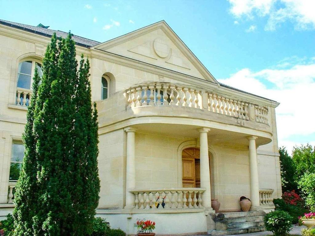 een groot wit huis met een balkon en een boom bij La demeure d'Iris in Bougival