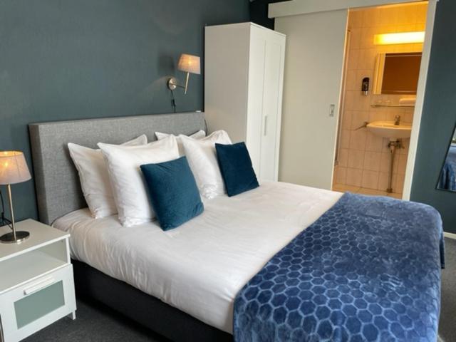 a bedroom with a large bed with blue and white pillows at Hotel De la Ruïne in Valkenburg