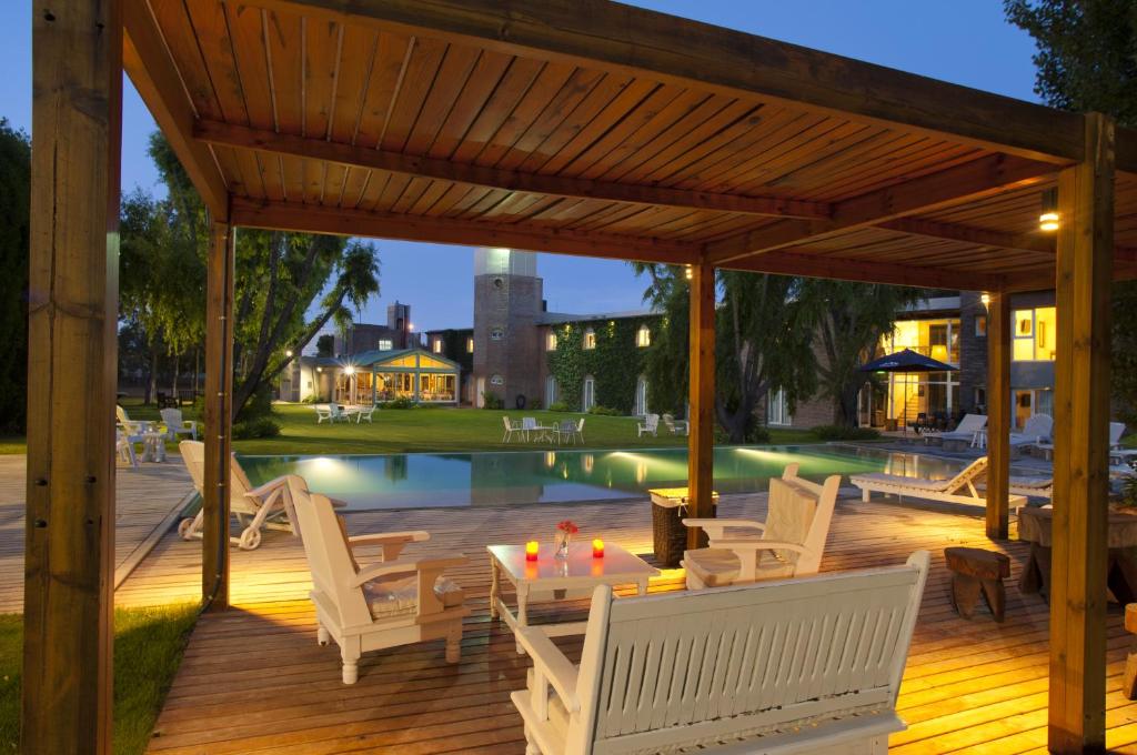 a deck with white chairs and a table and a pool at La Posada De Madryn in Puerto Madryn