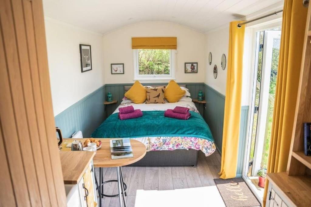 a small bedroom with a bed and a table at Close to Nature Easy to Find shepherd's hut in North Molton