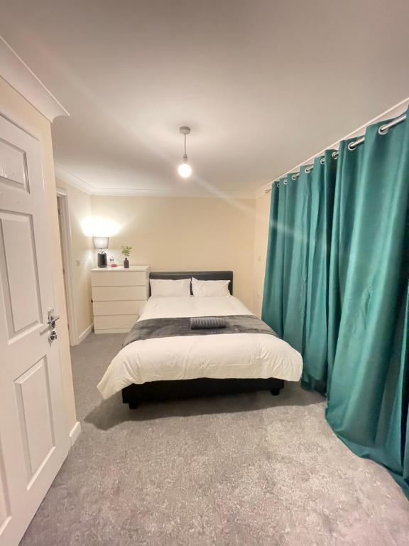 a bedroom with a large bed with blue curtains at Relaxing double rooms in a beautiful house in Ipswich