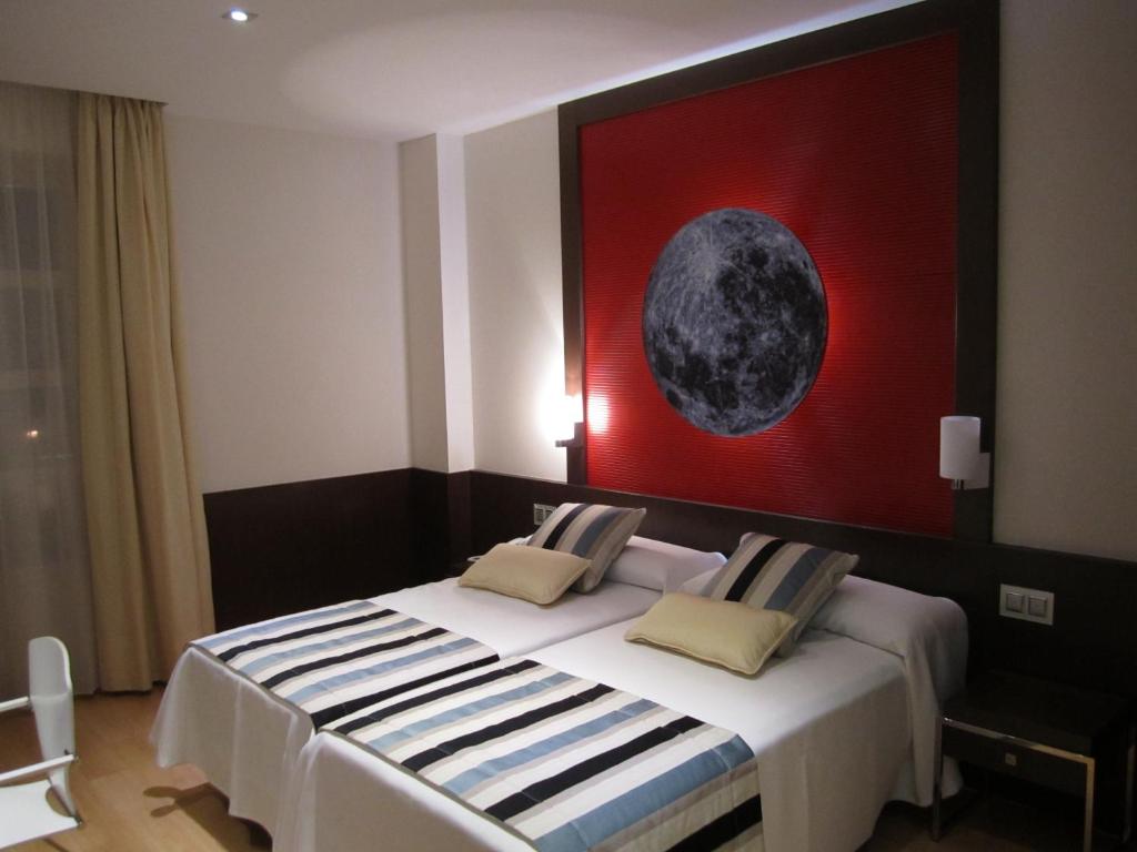 un dormitorio con una cama con una pintura de la luna en Hotel Vía Gótica, en Burgos