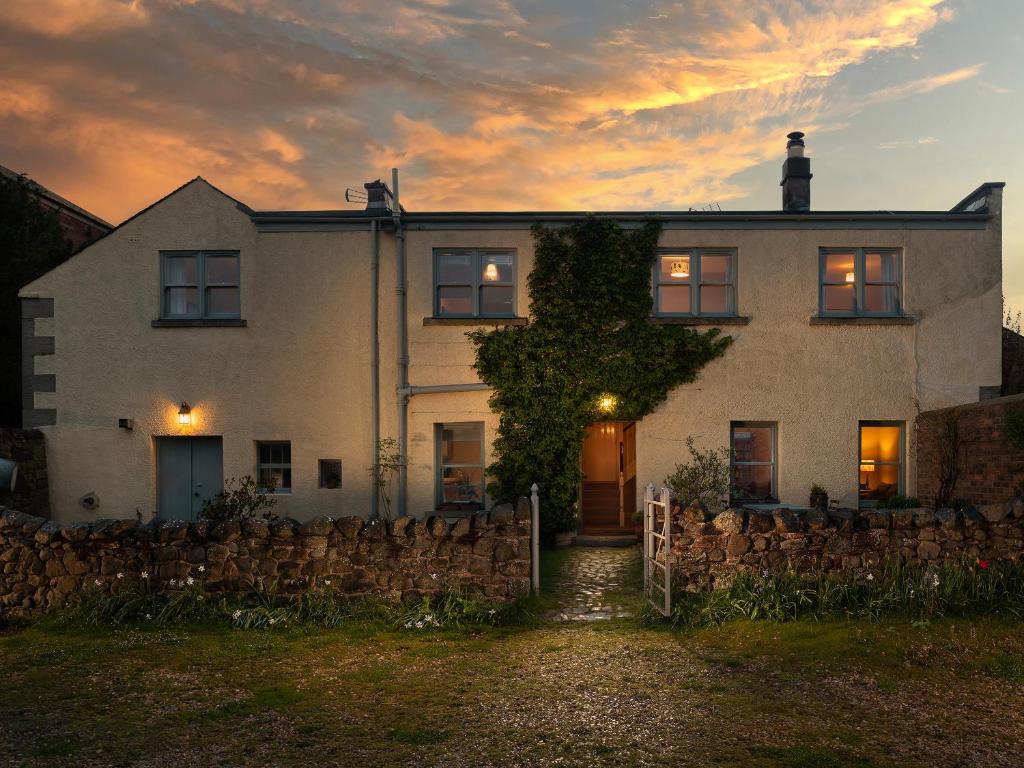 una gran casa blanca con una valla delante en Stable Yard Cottage, en Greenlaw