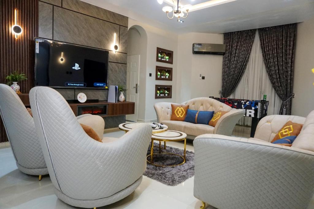 sala de estar con sillas blancas y TV en Luxurious Three-Bedroom Apartment In Wuye Abuja - New Base Apartments, en Dakibiu