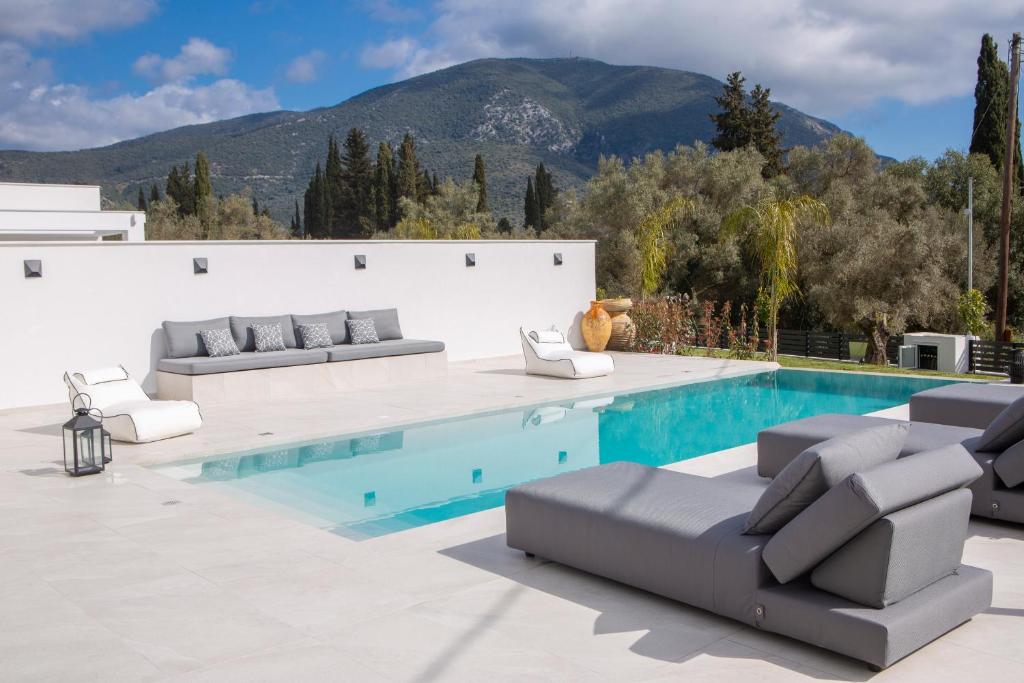 einen Pool mit Sofas und Stühlen neben einem Pool in der Unterkunft Eros - Afroditi Villas Collection in Nydri
