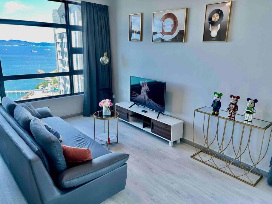 a living room with a blue couch and a tv at CC Suites Jesselton Quay - Seaview - 2Bedroom in Kota Kinabalu