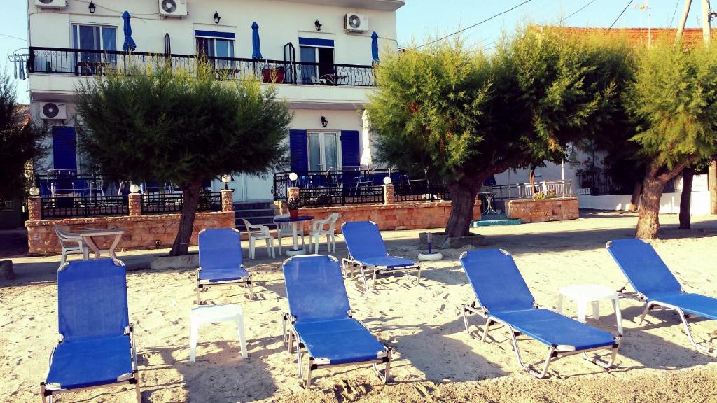 un gruppo di sedie e tavoli blu e alberi di Rooms Ntontas a Prinos