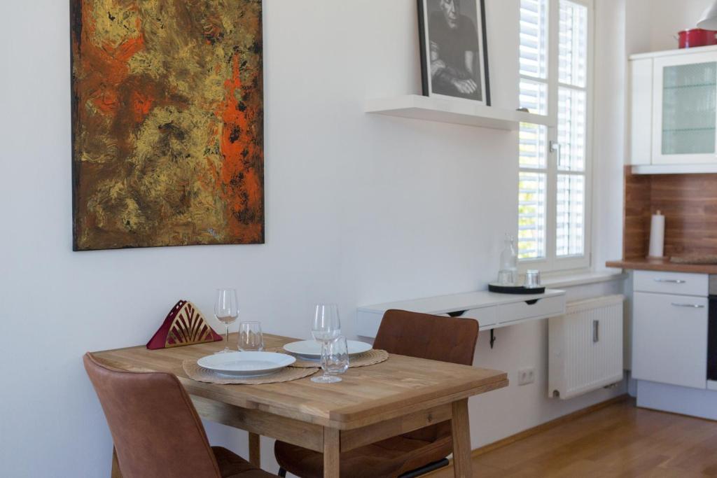 uma cozinha com uma mesa de madeira com cadeiras e um quadro em Pleasant City Apartment em Graz