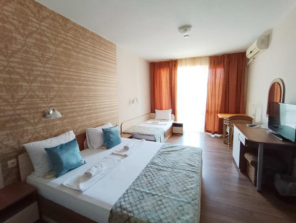 ein Hotelzimmer mit einem großen Bett und einem Schreibtisch in der Unterkunft Семеен Хотел Детелини in Primorsko