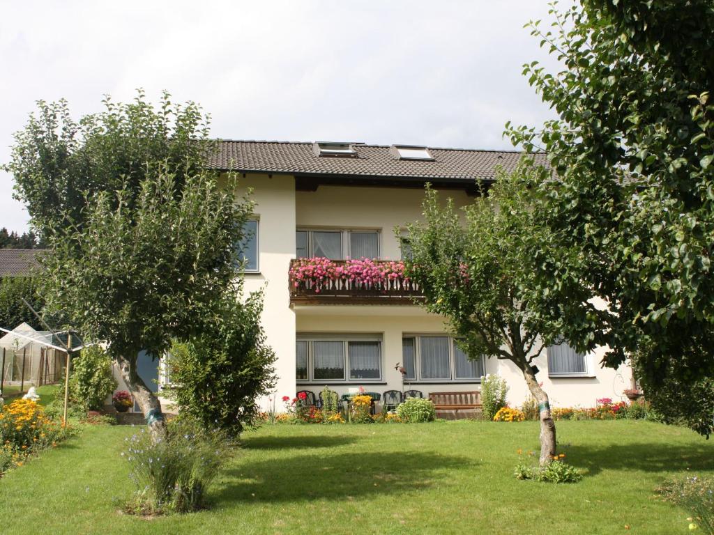 Ferienwohnung Triska في Balve: منزل به ساحه بها اشجار وزهور