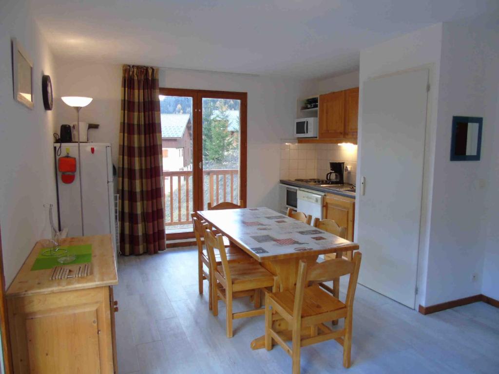 une cuisine avec une table, des chaises et un réfrigérateur dans l'établissement Appartement cosy à Valfréjus, 200m des pistes, balcon ouest, 6 pers, cuisine équipée, draps inclus - FR-1-561-23, à Valfréjus