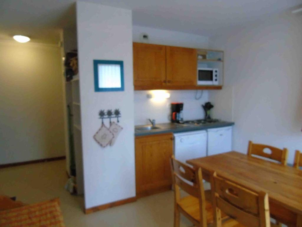 a kitchen with a table and a kitchen with a refrigerator at Appartement Valfréjus, 2 pièces, 4 personnes - FR-1-561-32 in Valfréjus