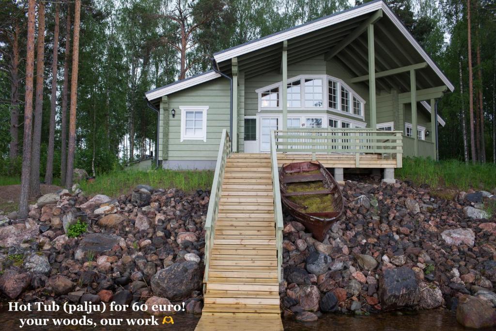 a small green house with a wooden walkway in front at SResort Saunas - hot tub, palju in Imatra