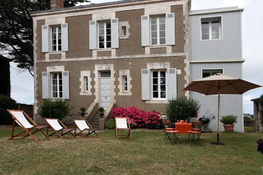 a group of chairs and an umbrella in front of a house at Les Hortensias Baie de La Baule -13 in Pornichet