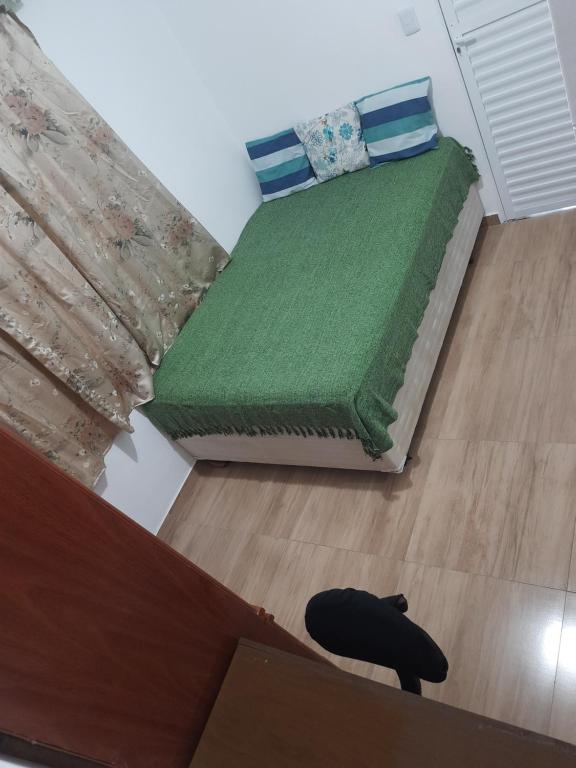 a bedroom with a bed with a green comforter at Hostel Sancris in São José dos Campos