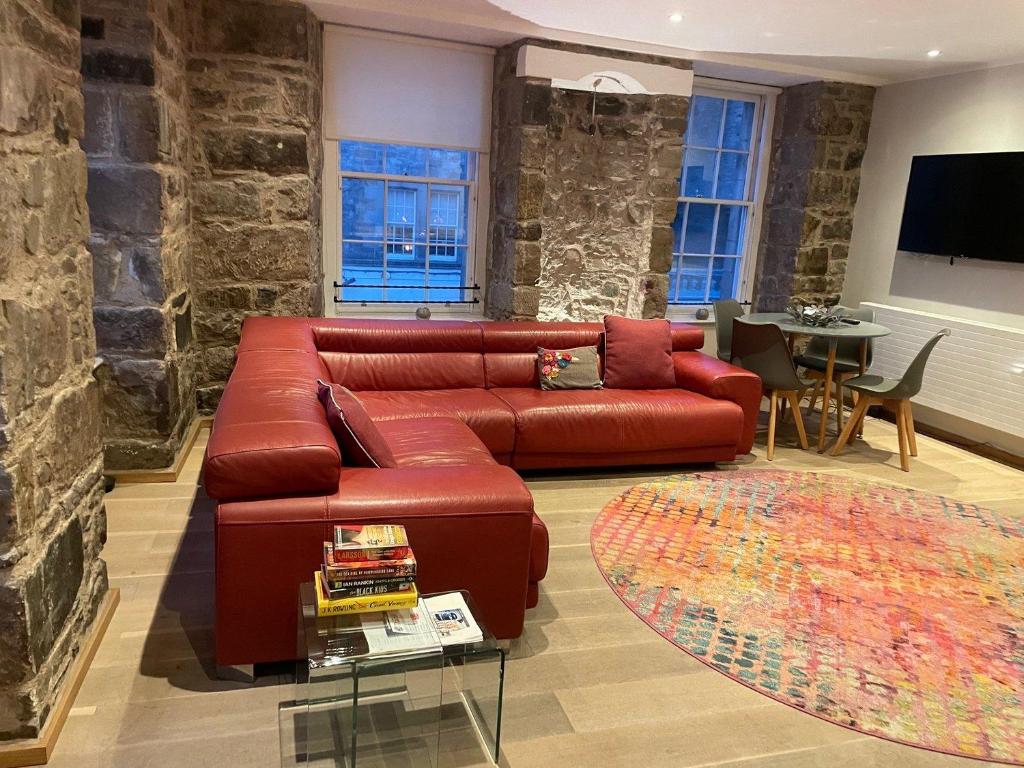 een woonkamer met een rode leren bank en een tafel bij JOIVY Elegant 2BR Home at The Heart of the Royal Mile in Edinburgh
