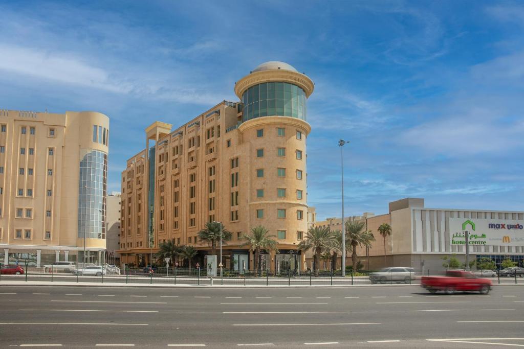 a building with a tower on top of a parking lot at Millennium Hotel Doha in Doha