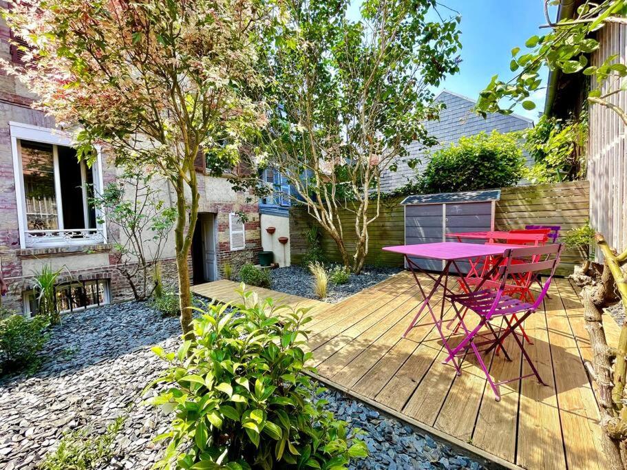 una mesa rosa y sillas en una terraza de madera en Le Villervillais CLS Deauville en Villerville