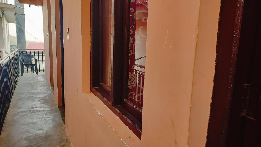 un couloir avec une fenêtre sur le côté du bâtiment dans l'établissement Neeraj Homestay, à Dharamshala