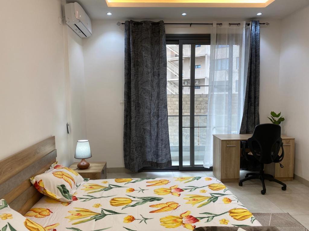 1 dormitorio con cama, escritorio y ventana en CHEZ CODOU FANN - POINT E, en Dakar