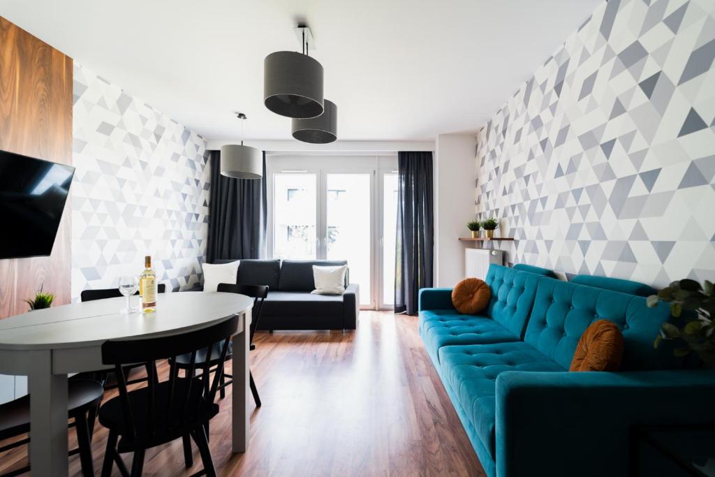 a living room with a blue couch and a table at Big Apart - Atal Towers - 3 Rooms - Private Parking Place in Wrocław