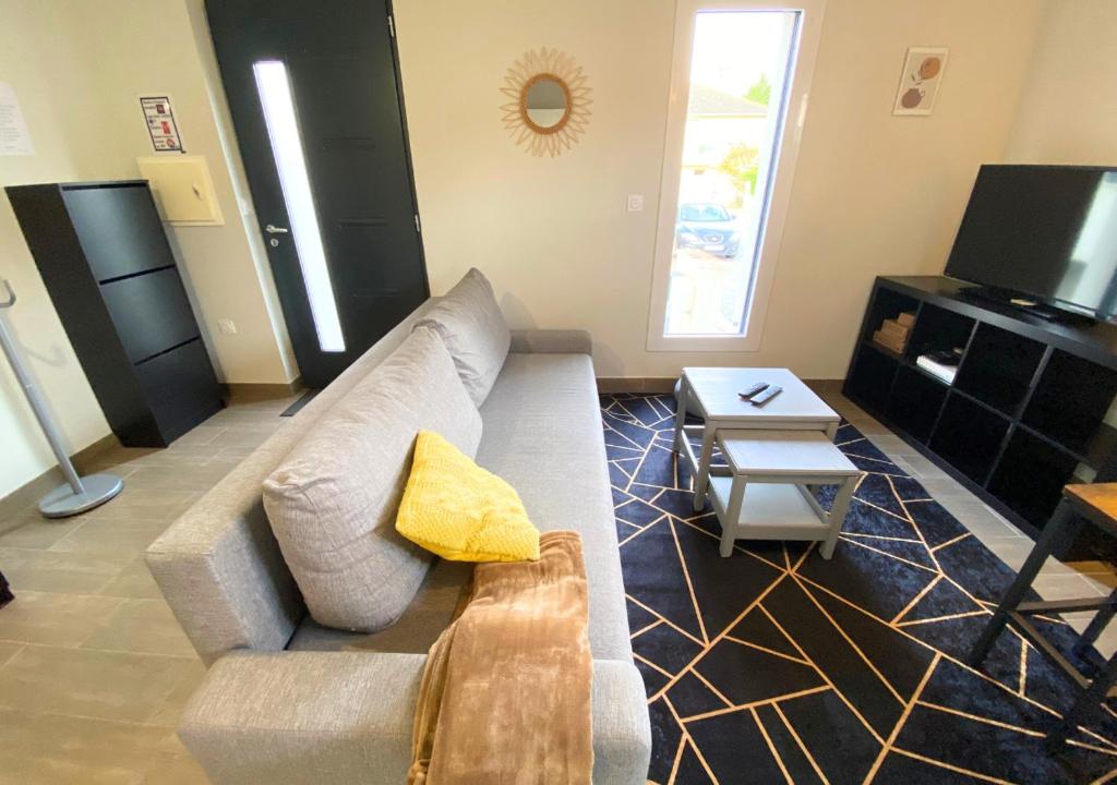 uma sala de estar com um sofá e uma mesa em Aux Pommiers - Poitiers CHU - CAMPUS - La Conciergerie em Poitiers