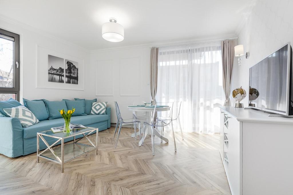 a living room with a blue couch and a table at Flatbook - Old Town Deluxe Apartments Sauna & Parking in Gdańsk
