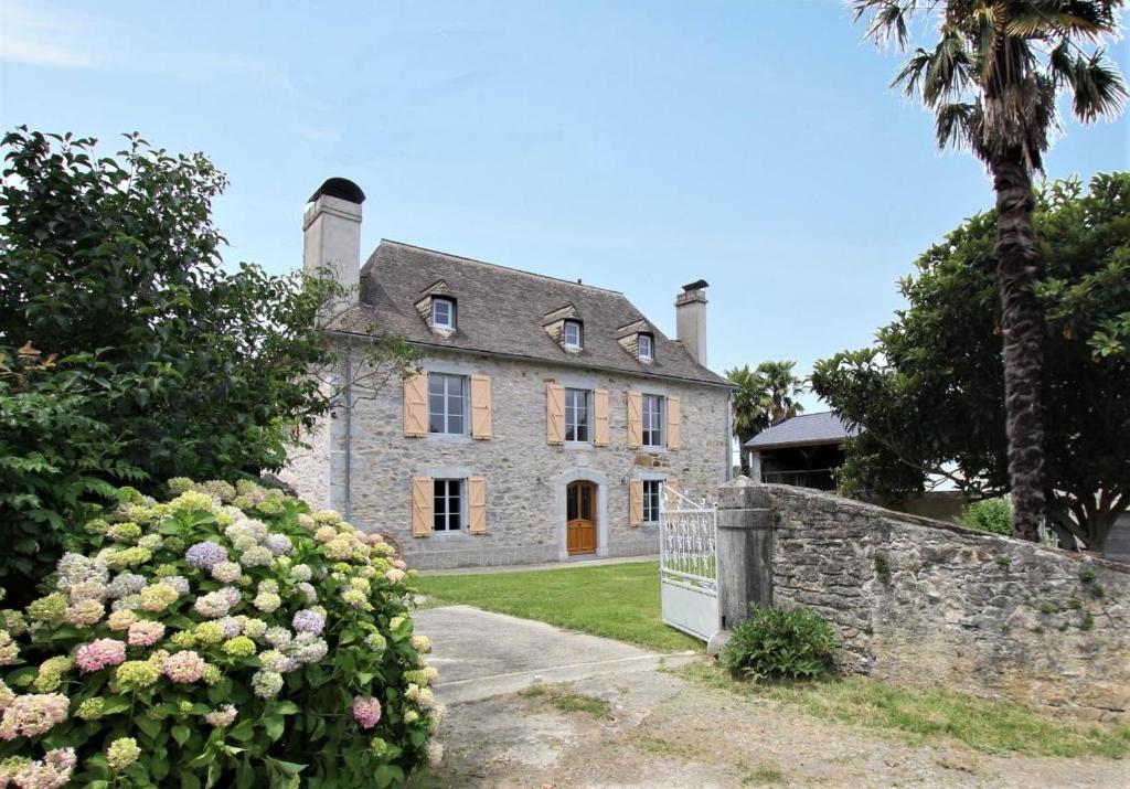 an old stone house with a fence and flowers at Chez zézé in Asson