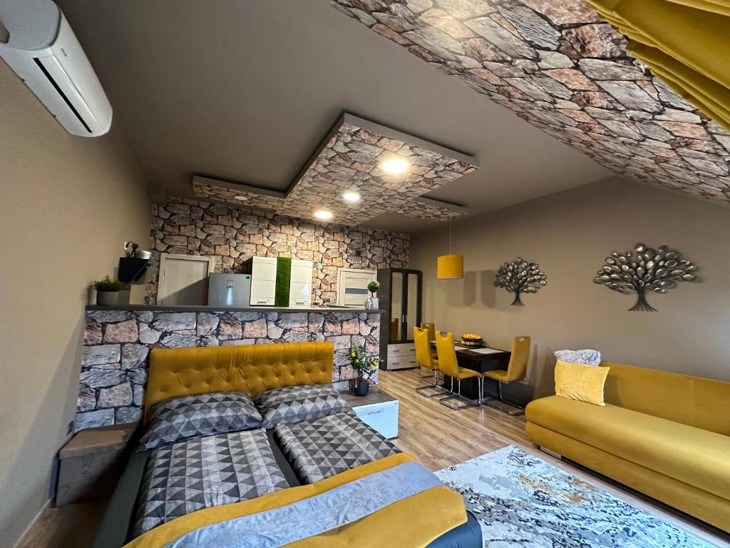 a living room with a bed and a stone wall at Gold Downtown Apartman in Debrecen