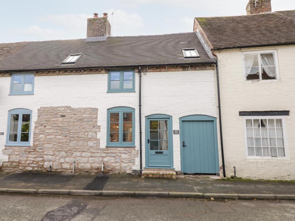 an old stone house with blue doors on a street at Tannery Cottage in Much Wenlock
