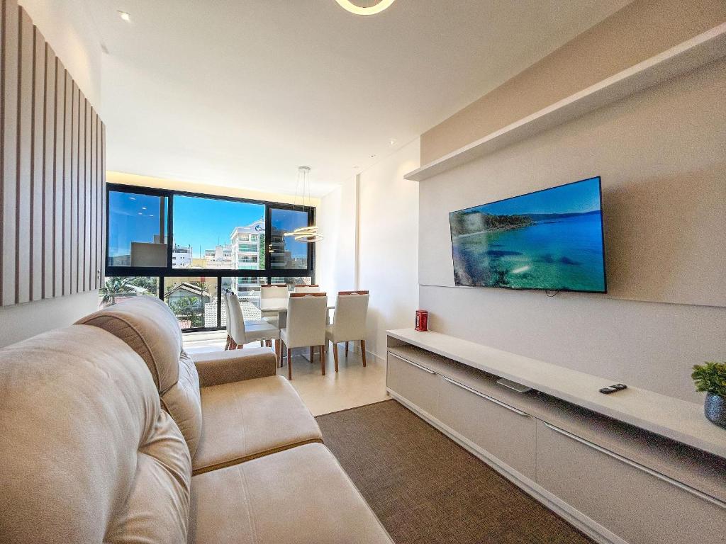 sala de estar con sofá y TV en Apto NOVO, com piscina, 250m da praia, en Bombinhas