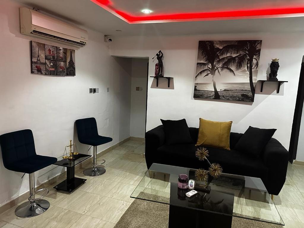 a living room with a black couch and two chairs at Osmosis Ikoyi in Lagos