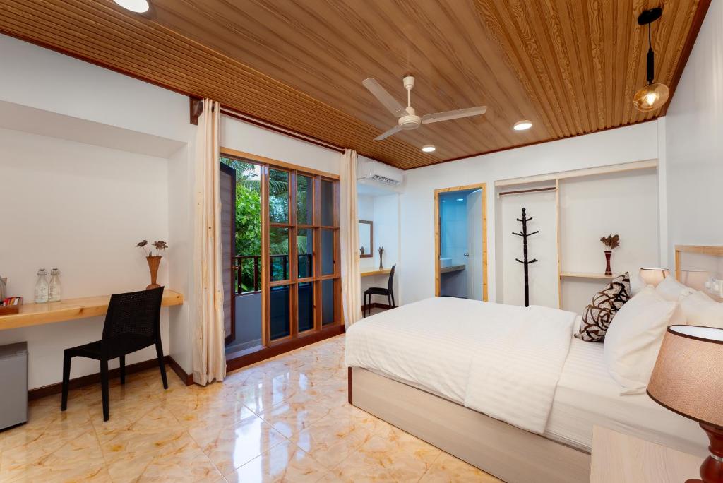 1 dormitorio con cama, escritorio y ventana en Hudhuveli Kamadhoo, en Milaidhoo