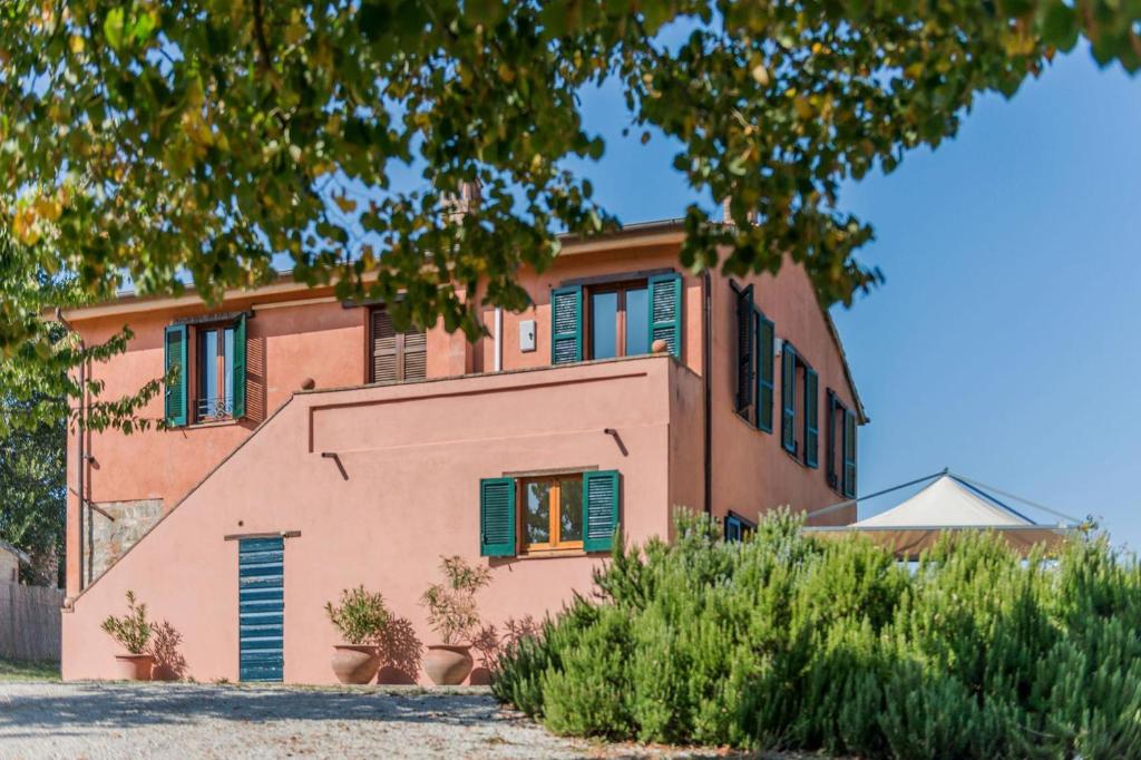 una casa rosa con persiane verdi di Casale Nocciolo 9 a Bevagna