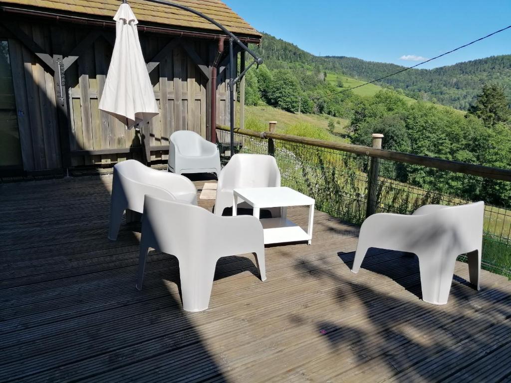 un grupo de sillas y mesas blancas en una cubierta en Ferme des boudieres en Fresse-sur-Moselle