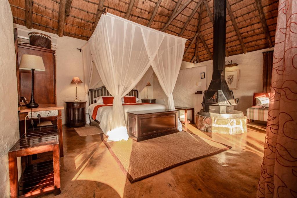a bedroom with a bed and a fireplace at Tanamera Lodge in Hazyview